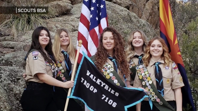 Female scouts pose with a flag.