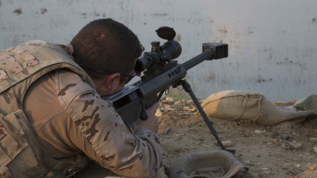 Service member looks in weapon viewfinder