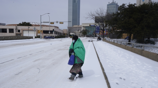 A woman wrapped in a blanket crosses the street near downtown Dallas.