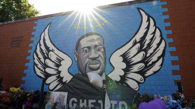 the sun shines above a mural honoring George Floyd