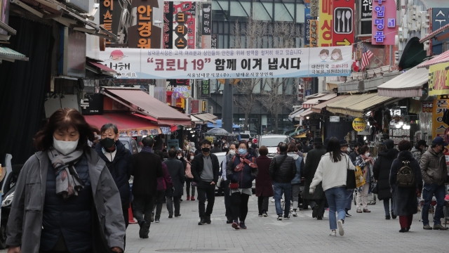 People wearing face masks walk through a market in Seoul, South Korea,