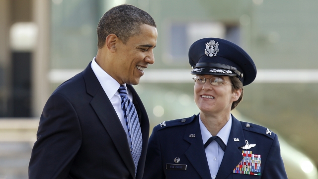 Former President Barack Obama walks with then Col. Jacqueline D. Van Ovost