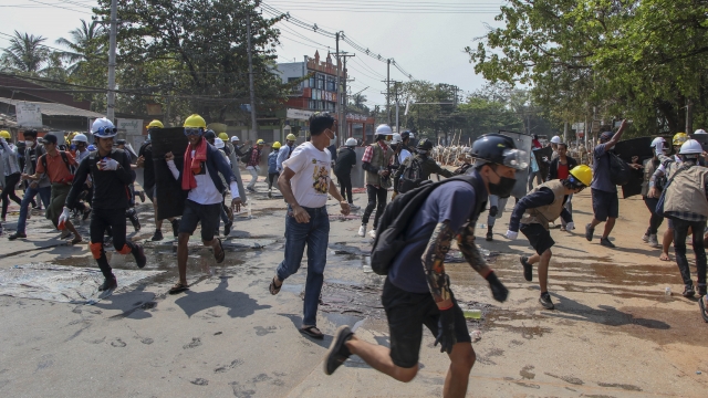 Anti-coup protesters scatter after police fire sound grenades and fire rubber bullets in Yangon, Myanmar