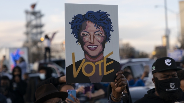 People in the crowd hold up an image of Stacey Abrams