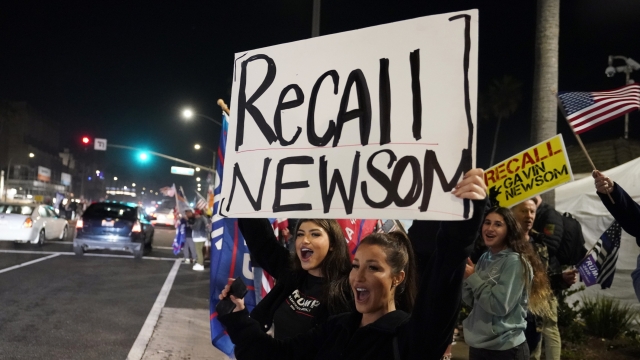 Demonstrators shout slogans while carrying a sign calling for a recall on Gov. Gavin Newsom during a protest.