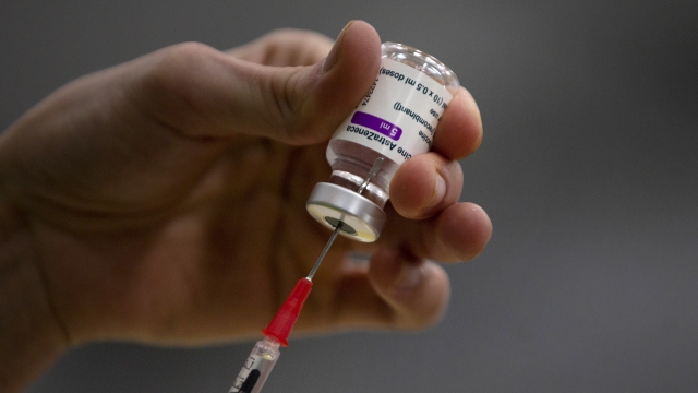 A pharmacist prepares a syringe from a vial of the AstraZeneca coronavirus vaccine.