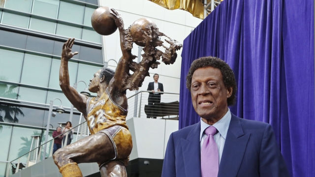 Elgin Baylor stands next to a statue honoring him outside the Staples Center in Los Angeles