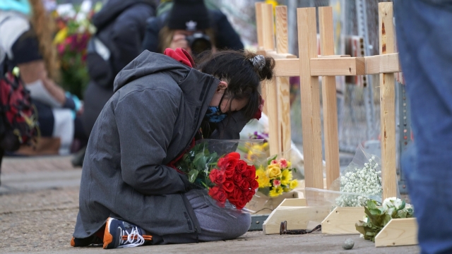 An employee of the grocery store kneels in front of crosses placed in honor of the victims.