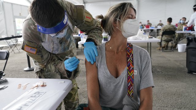 Liana Fonseca looks away as she receives the Pfizer COVID-19 vaccine