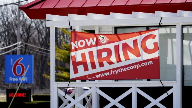 A "now hiring" sign outside a restaurant.