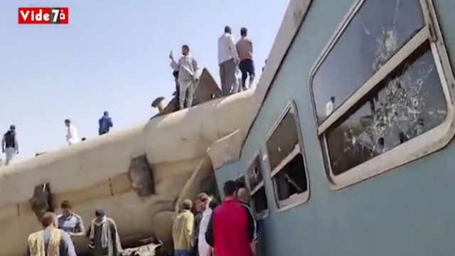 image provided by Youm7 shows crowds of people gathered around mangled train carriages