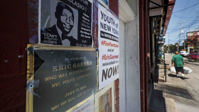 A memorial plaque for Eric Garner affixed to a building wall below his image, at the site where he died in a police chokehold