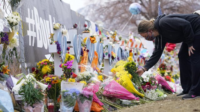 A mourner places a bouquet by the temporary fence line outside the