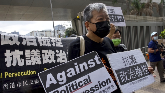 Pro-democracy activist holds signs outside a Hong Kong courthouse.