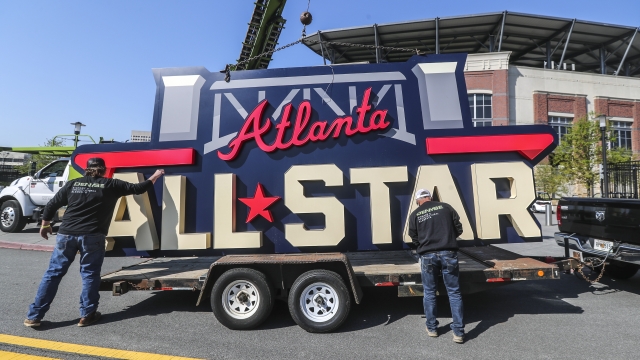 Workers load an All-Star sign onto a trailer