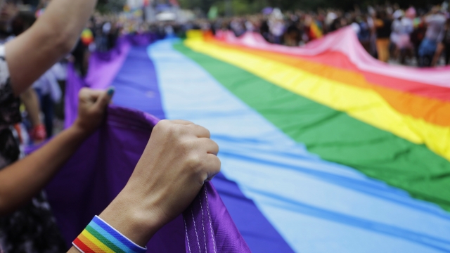 People holding LGBTQ rainbow flag