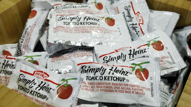 Packets of Simply Heinz ketchup fill a cafeteria condiment box.