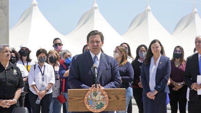 Florida Gov. Ron DeSantis, center, speaks during a news conference surrounded by officials and cruise workers.
