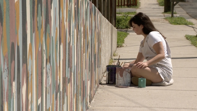 Woman paints on a wall.