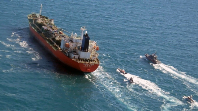 Seized South Korean ship is escorted by Iranian military boats on the Persian Gulf.