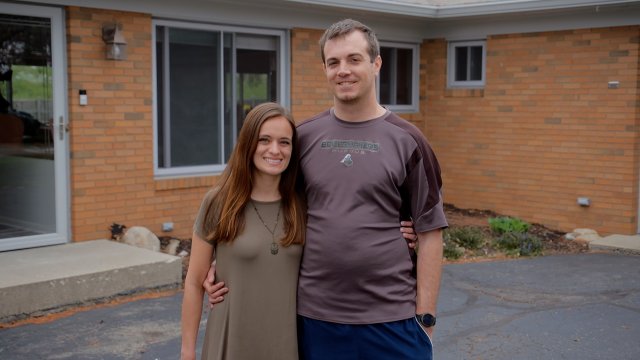 Billy and Tori, who foster migrant kids, in front of their house