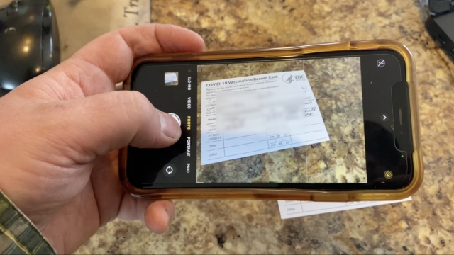 Man takes a photo of his vaccine card.