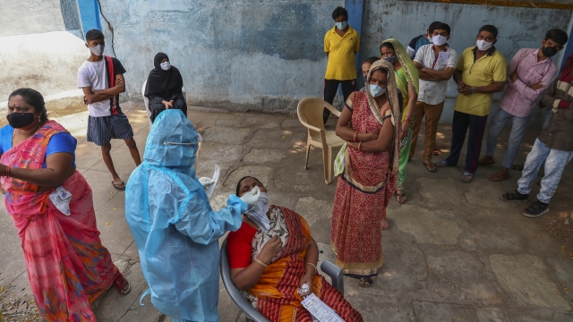 A health worker takes a nasal swab sample of a woman to test for COVID-19