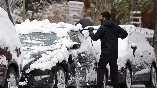 A motorist clears snow from his car after a storm.