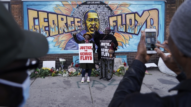People pose for pictures in front of a mural for George Floyd after a guilty verdict