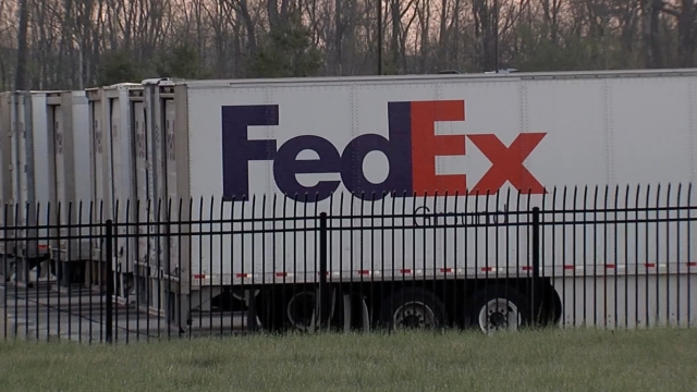 FedEx trucks sit in a parking lot.