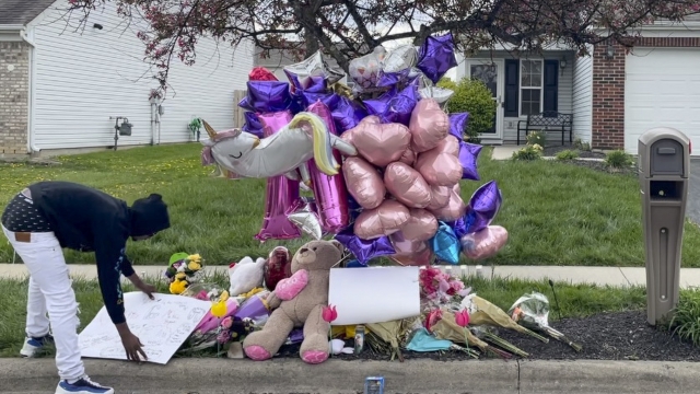 A man adjusts a sign near a memorial at the scene in the Columbus, Ohio neighborhood where Ma'Khia Bryant was killed.