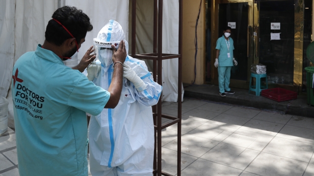 a health worker adjusts the face shield of another as she prepares to go inside a quarantine center for COVID-19 patients