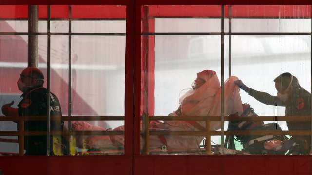 Emergency medical technicians wheel a patient into Elmhurst Hospital Center's emergency room.