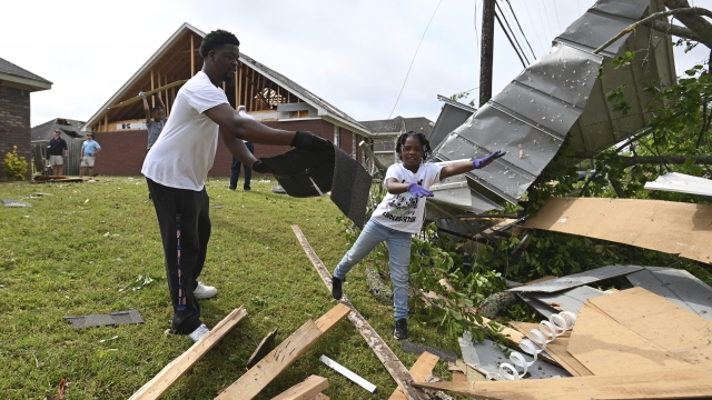 A father and daughter clean up debris around their residence