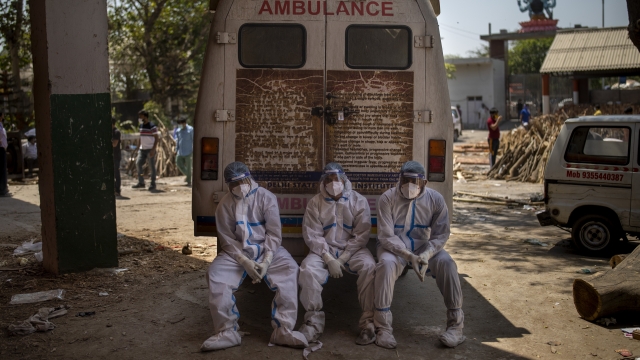 Exhausted workers who carried the dead for cremation sit on the rear step of an ambulance in New Delhi, India.