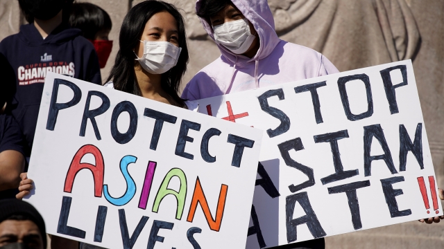 People hold signs as they attend a rally to support Stop Asian Hate.