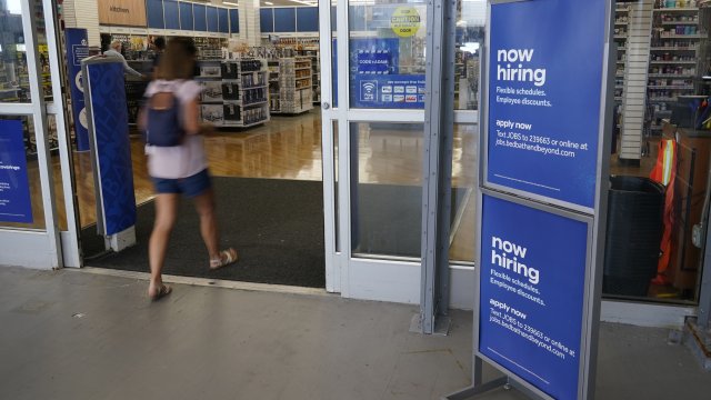 A sign looking to hire employees is displayed at the entrance to a Bed, Bath and Beyond store.