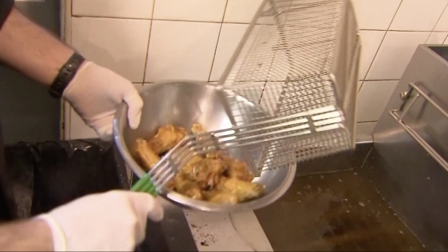 Man dumps chicken wings into a bowl.