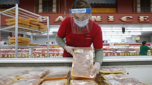 A worker restocks chicken in the meat product section at a grocery store in Dallas, Texas