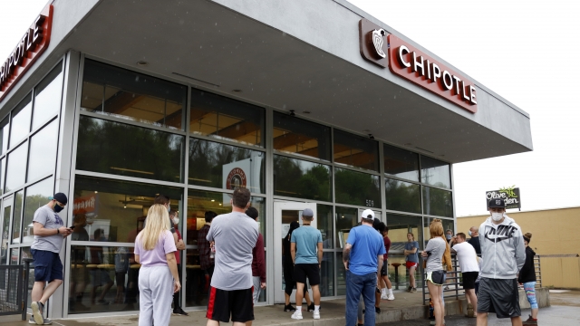 A crowd waits outside a Chipotle restaurant
