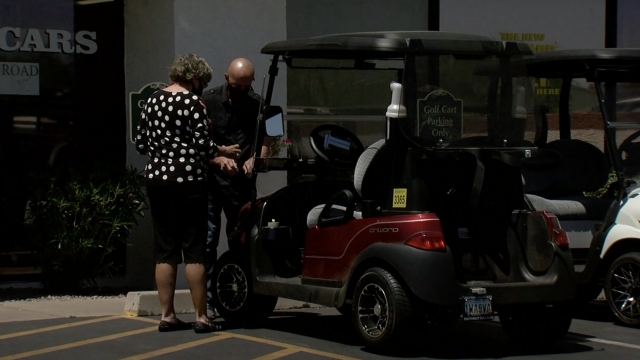 Woman stands next to a golf cart.