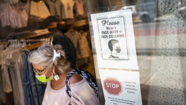 A customer wearing a protective mask exits a store