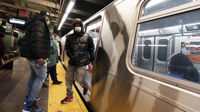 Commuters wear masks stepping on and off a subway car, in New York.