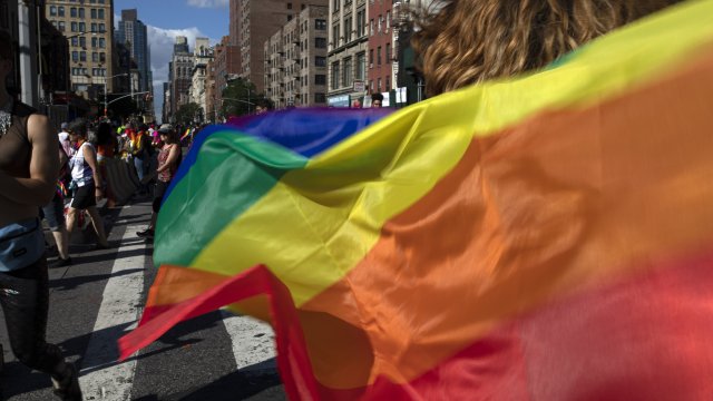 Parade-goers carrying rainbow flags walk down a street during the LBGTQ Pride march in New York.