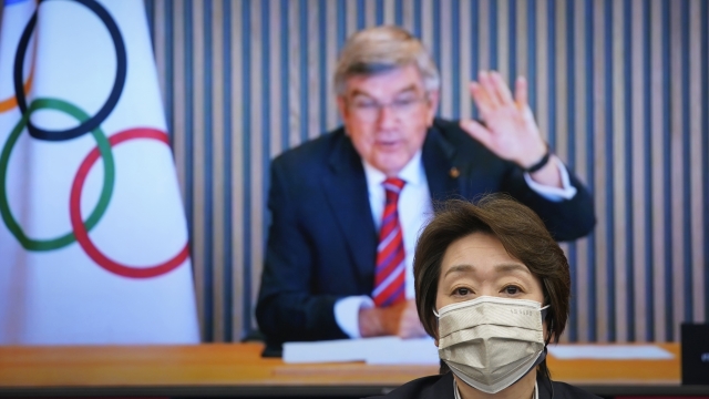 IOC President Thomas Bach, on a screen, waves to Tokyo 2020 Organizing Committee President Seiko Hashimoto at a meeting.