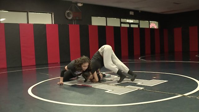Girls wrestle on a mat.