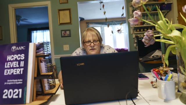 Ellen Booth, 57, studies at her kitchen table to become a certified medical coder, in Coventry, R.I., Monday, May 17, 2021.