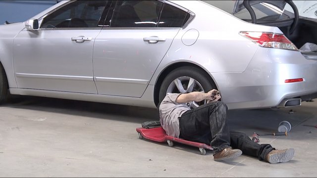 A mechanic works on a car.