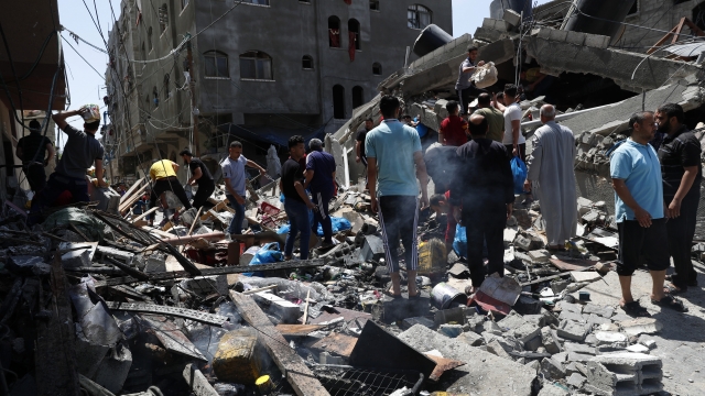 People inspect the rubble of destroyed residential building, which was hit by Israeli airstrikes