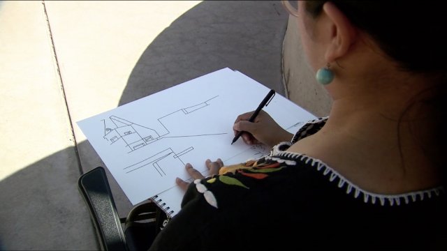 Woman draws on paper.
